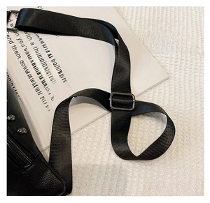 Detail of adjustable thick woven shoulder strap and silver metal buckle on a leather bag