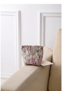 Close-up of floral jacquard makeup bag with gold flower zipper and H&R BAG logo