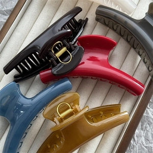 Top view of five colorful 11cm curved shark hair clips on a beige jewelry tray