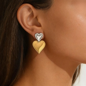 Close-up of dual-tone gold and silver heart earrings worn by a female model