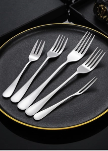 Detailed close-up of various stainless steel forks arranged on a premium black ceramic plate