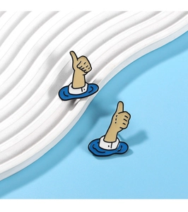 Detailed view of thumb-up enamel pins featuring blue wave patterns on white base