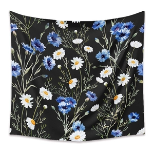 Close-up of bohemian tapestry fabric showing blue and white floral prints on black background