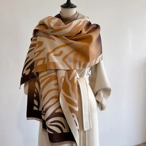 Elegant cashmere-like scarf with brown leaf patterns and fringe on a beige coat