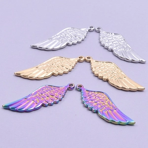 Polished stainless steel wing pendants in gold, silver and rainbow colors on purple surface