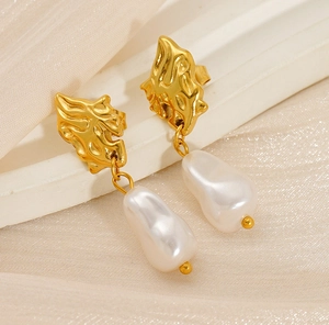 Detail shot of golden irregular metal studs with white baroque pearl drop earrings