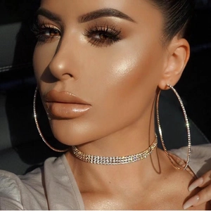 Close-up of sparkling oversized crystal hoop earrings and multi-row rhinestone choker