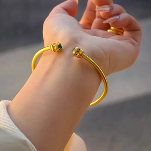 Elegance 24k gold plated open bangle with green zircon stone on a woman's wrist