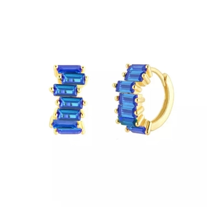Vue détaillée de boucles d'oreilles huggies dorées avec cinq zircons bleus taille baguette