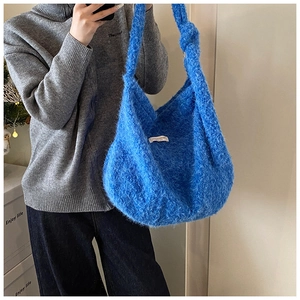 Detail of blue plush shoulder bag featuring soft knit texture and knotted strap design