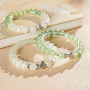 Detailed close-up of beaded fish bracelets with light green and milky white jade beads