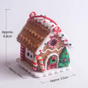 Detail of gingerbread house hanging ornament with white icing and red candy accents