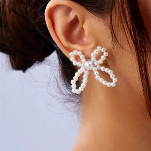 Close-up of elegant bow-shaped pearl earrings worn by a model to show size and fit