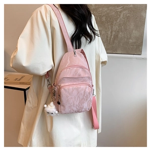 Dettaglio del marsupio in nylon rosa con trama a pieghe e ciondolo in peluche bianco