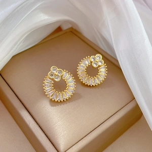 Close-up of golden four-leaf clover earrings with zircon inlay on jewelry box