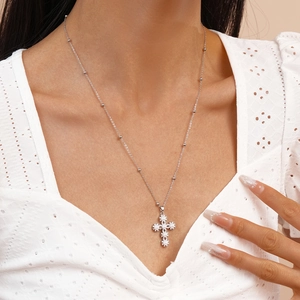 Detail of silver cross necklace featuring white pearls and shimmering cubic zirconia stones