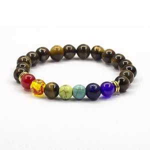 Close-up detail of natural tiger eye and colorful chakra stone bead bracelet with gold rings.