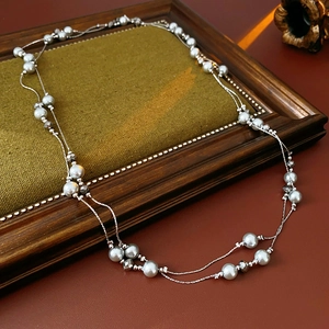 Detail of layered silver necklace with grey crystal beads on vintage wood frame