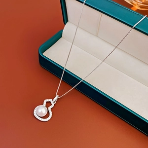 Close-up of zircon gourd pearl pendant necklace in a premium dark green jewelry gift box