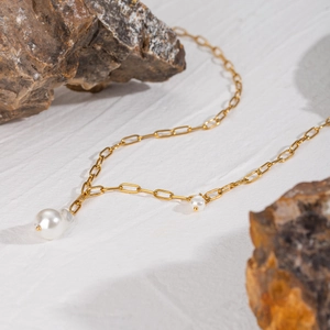 Detail of 18k gold paperclip chain necklace with baroque pearls on stone