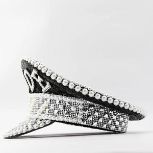 Détail d'un chapeau noir à paillettes avec perles blanches, strass argentés et motif NY