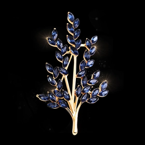 Elegant gold wheat brooch with deep blue crystals on a high-end fashion accessory