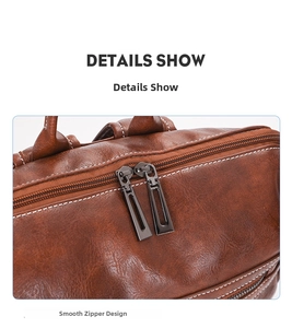 Detail view of the smooth dual metal zippers and white stitching on brown leather backpack