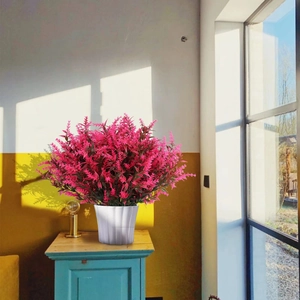 Pink lavender in white ribbed pot on wooden desk with warm natural window light shadows
