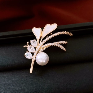 Macro detail of 14K gold flower brooch with white pearl, zircon and heart shell petals