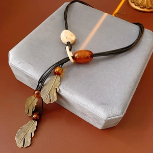 Detail of bohemian necklace with bronze leaves and amber resin beads on black cord