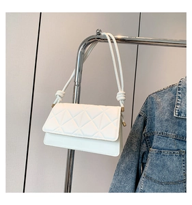 Detail of white quilted crossbody bag with geometric lattice pattern and knotted strap