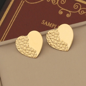 Detail view of heart stud earrings with mixed hammered and polished golden finish