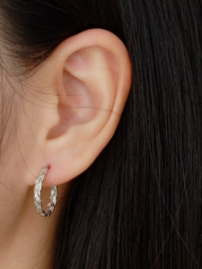 Macro view of S925 sterling silver hoop earring with vintage woven chain texture on ear