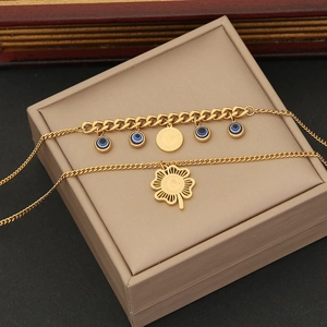 Gold double-layered necklace featuring evil eye charms and a hollow flower pendant