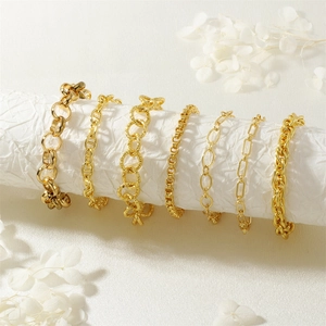 Set di bracciali a catena dorati minimalisti esposti su un rotolo di carta bianca