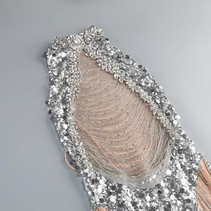 Macro detail of silver sequins, crystal rhinestones, and beaded fringe on mesh evening gown