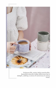 Detail of speckled ceramic mugs in purple, green and beige held in a lifestyle setting