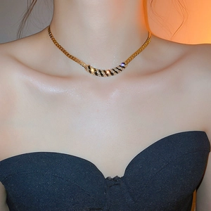 Close-up of gold snake chain necklace with black enamel stripes and sparkling crystals
