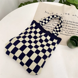Detailed texture of thick knitted black and white checkerboard tote bag on a white table
