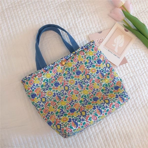 Detailed close-up of floral lunch bag with denim handle and vintage gold button closure