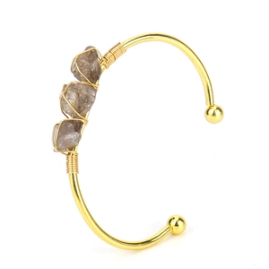 Detailed shot of handmade gold wire-wrapped bracelet with natural raw amethyst crystals