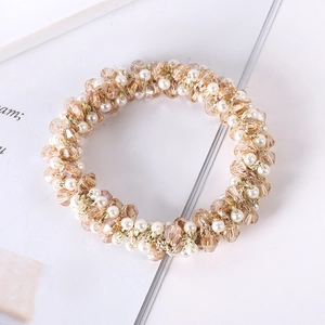 Detail of elegant champagne crystal and white pearl hair tie with woven gold wire