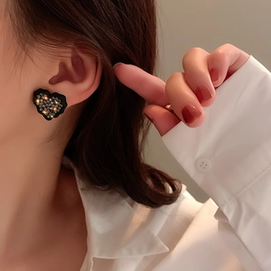 Gros plan d'élégantes boucles d'oreilles cœur noir avec diamants sur un modèle féminin