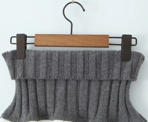 Detail of soft charcoal grey knitted top showing textured collar on wooden hanger