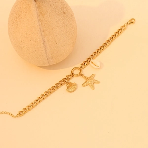 Detail of gold starfish and shell charms on a stainless steel ocean-themed bracelet