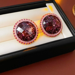 Detail view of vintage resin earrings with gold trim and pink crystals on soft white padding