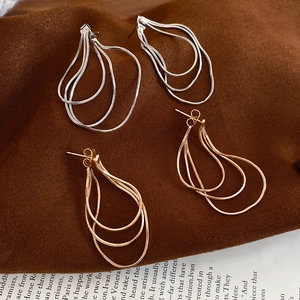 Vue détaillée de boucles d'oreilles à pompons dorés et argentés avec chaînes serpent fines