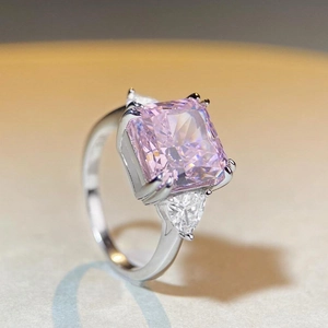 Gros plan d'une bague avec pierre rose taille radiant et pierres latérales en argent