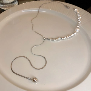 Macro detail of silver Y-shaped necklace with pearl and irregular silver beads