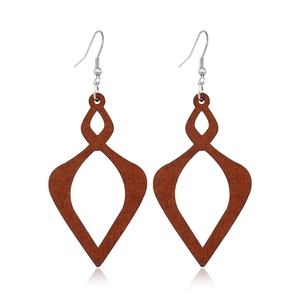 Macro detail of rhombus hollowed dark brown wood earrings with metal hooks and natural grain